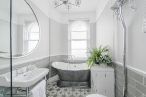 a bathroom with a tub and a sink and a mirror at The Surveyors House Devon, Luxury Victorian Villa in Torbay in Kingskerswell