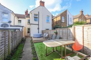 a small backyard with a wooden table and chairs at Maidstone Best 1 Bed City Centre Flat - Fast Wi-Fi in Maidstone