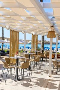 an outdoor patio with tables and chairs and the ocean at Pavlo Napa Beach Hotel in Ayia Napa