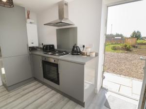 eine Küche mit Herd oberer Ofen neben einem Fenster in der Unterkunft Old Colliery Cottage in Shilbottle