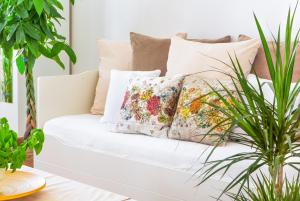 a white couch with pillows in a living room with plants at 5 Min zur Elbe, Helle Geräumige 2-Raum-Whg, Neustadt, Top Lage in Dresden