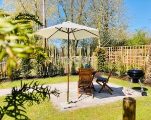 eine Terrasse mit einem Tisch, einem Sonnenschirm und einem Grill in der Unterkunft The BeeKeepers - Homely Luxurious Self Catering in Shelfanger