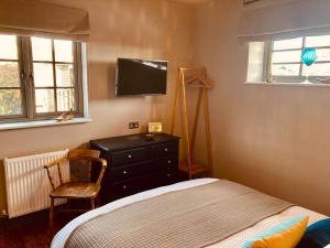 ein Schlafzimmer mit einem Bett, einer Kommode und einem TV in der Unterkunft The BeeKeepers - Homely Luxurious Self Catering in Shelfanger
