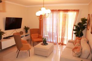 a living room with a couch and chairs and a tv at Las Cayenas Residéncial in Santo Domingo