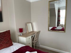 a bedroom with a mirror and a bed and a desk at The Sandrock in Clacton-on-Sea