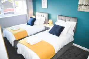 dwa łóżka siedzące obok siebie w pokoju w obiekcie 2ndHomeStays -Willenhall-Charming 3-Bedroom Home w mieście Walsall