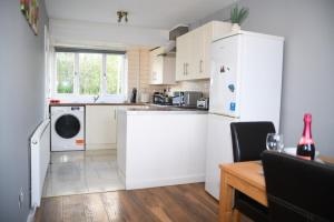 cocina con armarios blancos y nevera blanca en 2ndHomeStays -Willenhall-Charming 3-Bedroom Home, en Walsall