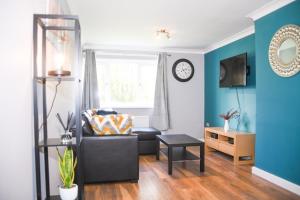 een woonkamer met een zwarte stoel en een klok bij 2ndHomeStays -Willenhall-Charming 3-Bedroom Home in Walsall