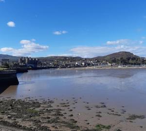 un cuerpo de agua con una ciudad en el fondo en Charming Mid Terrace Cottage en Conwy