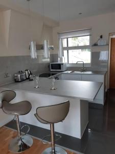 a kitchen with two bar stools and a sink at Charming Mid Terrace Cottage in Conwy