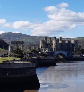 a large castle with a bridge over a river at Charming Mid Terrace Cottage in Conwy