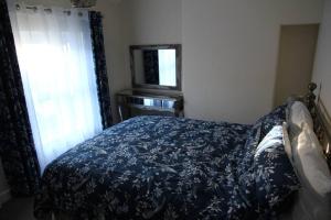 a bedroom with a bed with a blue bedspread and a window at Charming Mid Terrace Cottage in Conwy