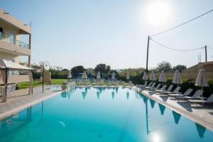 una gran piscina con sillas y sombrillas en Barbie Hotel Apartments, en Ialisos