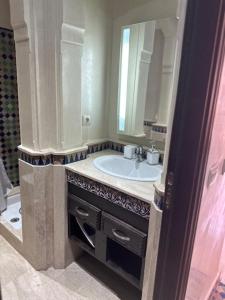 een badkamer met een wastafel en een spiegel bij APPARTEMENT MARRAKECH HIVERNAGE in Marrakesh