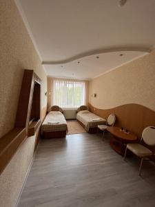 a room with two beds and a table and chairs at Оазис in Zalishchyky