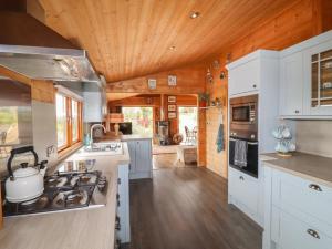 cocina con armarios blancos y techo de madera en Tilly's Lodge, en Doncaster