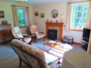 a living room with two chairs and a fireplace at Bridge of Bennie Cottage in Banchory