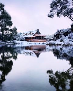 a house on a lake in the snow at Peppers Cradle Mountain Lodge in Cradle Mountain