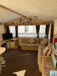 ein Wohnzimmer mit einem Sofa und einem TV in der Unterkunft The Vacation golden gate towyn in Kinmel Bay