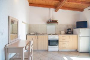 a kitchen with a table and a white refrigerator at Villa Theodora View Apartments Erato in Agios Georgios Pagon