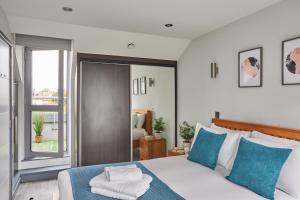 1 dormitorio con 1 cama con almohadas azules y blancas en Wembley Stadium by Viridian Apartments, en Londres