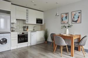 cocina con armarios blancos, mesa y sillas en Wembley Stadium by Viridian Apartments, en Londres