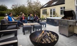 eine Gruppe von Personen, die auf einer Terrasse mit einer Feuerstelle sitzen in der Unterkunft The Willows in Laceby