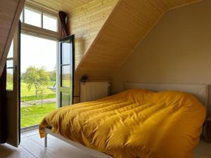 a bedroom with a yellow bed with a large window at Kleine Huisje in Ruinerwold