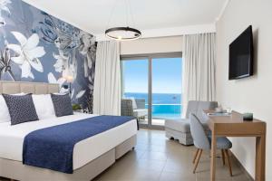 a hotel room with a bed and a desk and a view at Ajul Luxury Hotel & Spa Resort, a Registry Collection Hotel in Agia Paraskevi