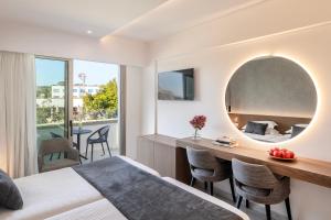 a bedroom with a bed and a desk with a mirror at Pavlo Napa Beach Hotel in Ayia Napa