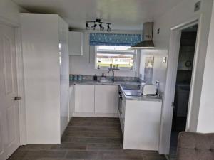 a kitchen with white cabinets and a sink and a window at Burgh Castle in Belton