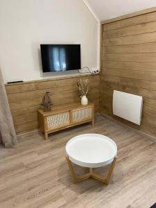 un soggiorno con tavolo bianco e TV di Le Nid du Cygne a Houlle