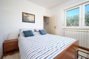 a white bedroom with a large bed with blue pillows at App Forza in Umag +19 photos