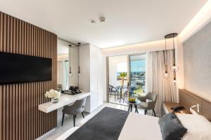 a hotel room with a king bed and a desk with a view at Pavlo Napa Beach Hotel in Ayia Napa