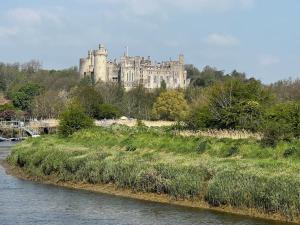a castle sitting on top of a hill next to a river at Quirky 1 bedroom barn on the river in Arundel in Arundel