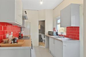 kuchnia z białymi szafkami i ścianą z czerwonej cegły w obiekcie Maidstone Best 1 Bed City Centre Flat - Fast Wi-Fi w mieście Maidstone