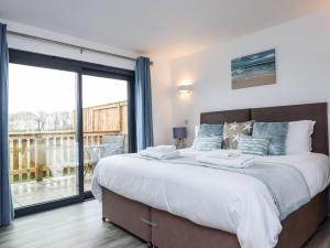 a bedroom with a large bed with a large window at Strawberry Bank - Nuthatch in Holsworthy