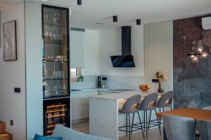 a kitchen with white cabinets and a counter with stools at Villa Vitrenik, Cista Velika, Makarska-Imotski in Velika Cista