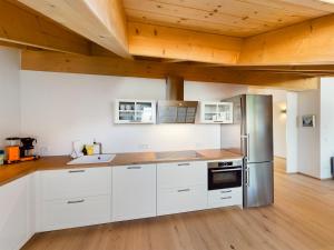 a kitchen with white cabinets and a wooden ceiling at Gipfelkreuz mit Sauna in Garmisch-Partenkirchen