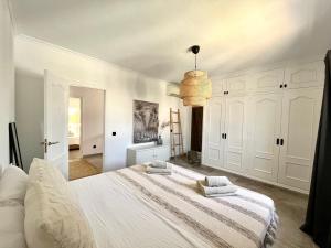 Habitación blanca con cama grande y lámpara de araña. en Celebrate Life's Precious Moments at Can Saca! en Sant Jordi