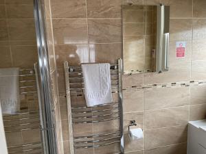 a bathroom with a shower with a towel and a mirror at The Sandrock in Clacton-on-Sea