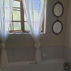 baño con bañera y ventana con cortinas en Irma's farmstay at the Nuy Valley Guesthouse, en Nuy