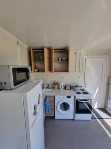 a kitchen with a white refrigerator and a microwave at Бунгало РАФИ в къмпинг Атлиман - гр. Китен in Kiten