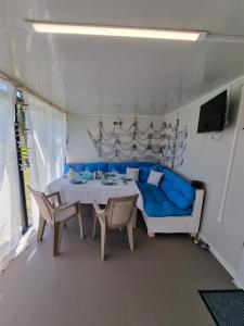 une salle à manger avec un canapé bleu et une table dans l'établissement Бунгало РАФИ в къмпинг Атлиман - гр. Китен, à Kiten