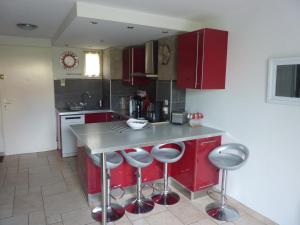 a kitchen with red cabinets and a counter with stools at Mas Provençal in Le Lavandou