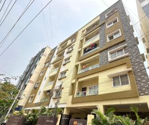 a tall yellow building with windows on a street at Autumn suites in Hyderabad