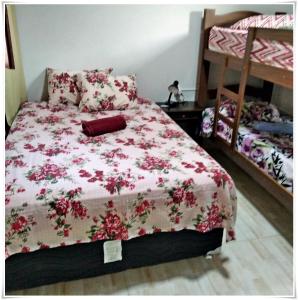 a bedroom with a bed with a pink floral bedspread at Pousada Seu Jorge in Campinas