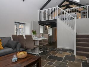 a living room with a couch and a table and stairs at Strawberry Bank - Pipistrelle in Holsworthy