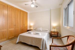 ein Schlafzimmer mit einem Bett und zwei Stühlen und einem Fenster in der Unterkunft Las Brisas Playa San Juan By Paramount Holidays in Guía de Isora