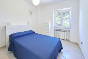 a white bedroom with a blue bed and a window at Villa Luminosa in Brindisi